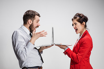 Image showing The young businessman and businesswoman with laptops on gray background