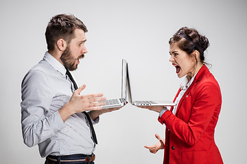 Image showing The young businessman and businesswoman with laptops on gray background