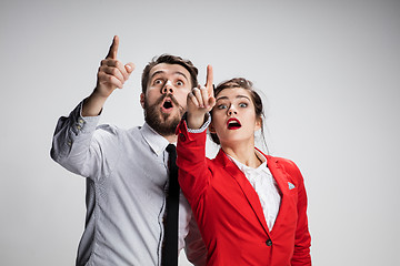 Image showing The surprised business man and woman showing up on a gray background