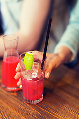 Image showing close up of hand with cocktail or juice and straw 