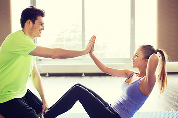 Image showing woman with personal trainer doing sit ups in gym