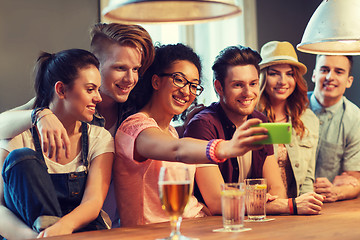 Image showing happy friends with smartphone taking selfie at bar