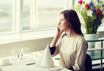 Image showing happy woman calling on smart phone at restaurant