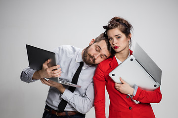 Image showing The young businessman and businesswoman with laptops  posing on gray background