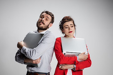 Image showing The young businessman and businesswoman with laptops  posing on gray background