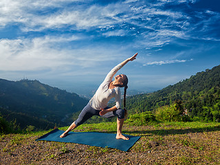 Image showing Woman practices yoga asana Utthita Parsvakonasana outdoors