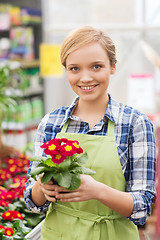 Image showing happy woman holding flowers in greenhouse