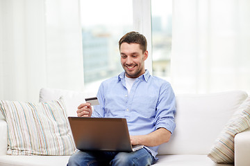 Image showing smiling man with laptop and credit card at home