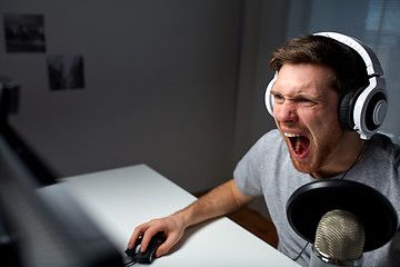 Image showing man in headset playing computer video game at home