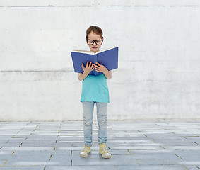 Image showing happy little girl in eyeglasses reading book