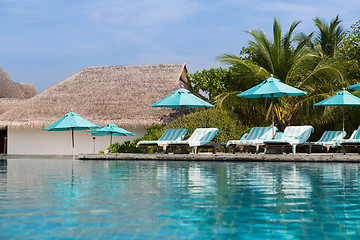 Image showing parasol and sunbeds by sea on maldives beach