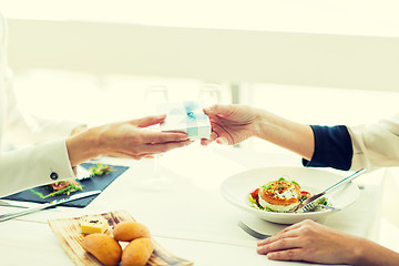 Image showing close up of women giving present at restaurant