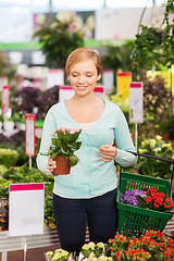 Image showing happy woman with shopping basket choosing flowers