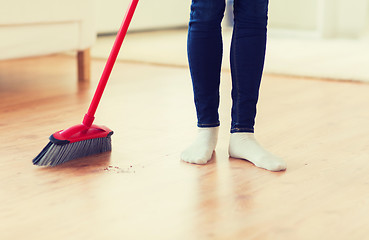 Image showing close up of woman legs with broom sweeping floor