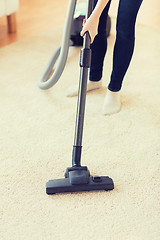 Image showing close up of woman legs with vacuum cleaner at home