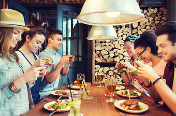 Image showing happy friends with smartphones picturing food