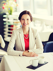 Image showing happy woman sitting at table in restaurant