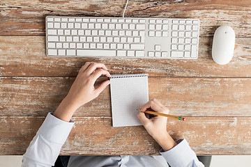 Image showing close up of hands with notebook and keyboard