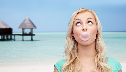 Image showing happy woman or teenage girl chewing gum on beach