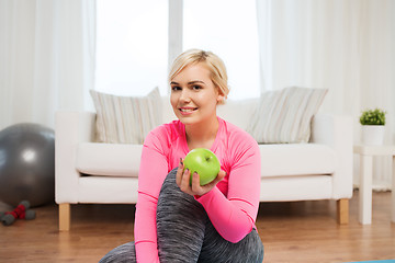 Image showing happy woman eating green apple at home