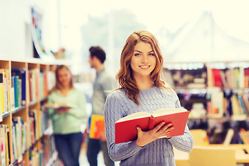 Image showing happy student girl or woman with book in library