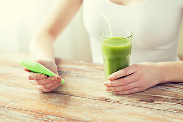 Image showing close up of woman with smartphone and green juice