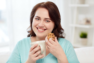 Image showing happy plus size woman with cup and cookie at home