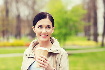 Image showing smiling woman drinking coffee in park