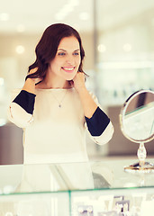 Image showing happy woman choosing pendant at jewelry store