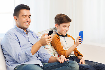 Image showing happy father and son with smartphones at home