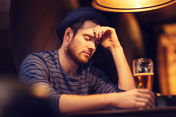 Image showing unhappy lonely man drinking beer at bar or pub