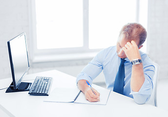 Image showing businessman with notebook and computer