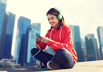 Image showing happy young woman with smartphone and headphones