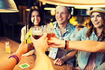 Image showing happy friends clinking glasses at bar or pub