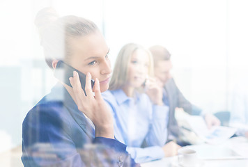 Image showing smiling business team with smartphones in office