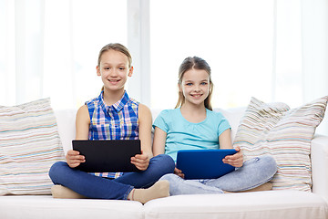 Image showing happy girls with tablet pc sitting on sofa at home