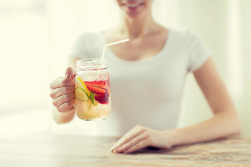 Image showing close up of woman holding glass with fruit water
