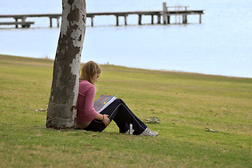 Image showing girl sitting against tree reading book