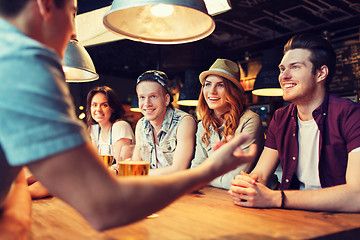 Image showing happy friends drinking beer and talking at bar