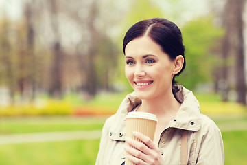 Image showing smiling woman drinking coffee in park