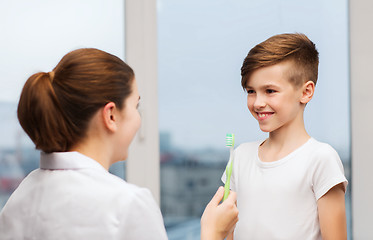 Image showing doctor with toothbrush and happy boy in clinic