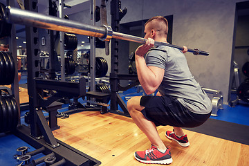 Image showing young man flexing muscles with bar in gym