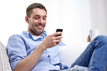 Image showing smiling man with smartphone at home