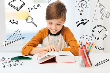 Image showing smiling, student boy reading book at home