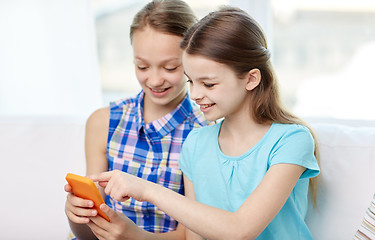 Image showing happy girls with smartphones sitting on sofa