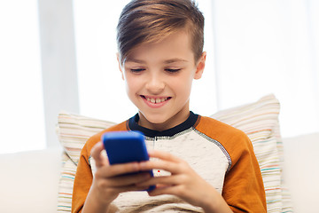 Image showing boy with smartphone texting or playing at home