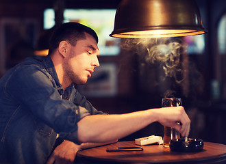 Image showing man drinking beer and smoking cigarette at bar