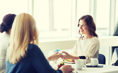 Image showing happy women giving birthday present at restaurant