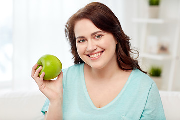 Image showing happy plus size woman eating green apple at home