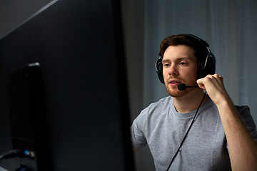 Image showing man in headset playing computer video game at home